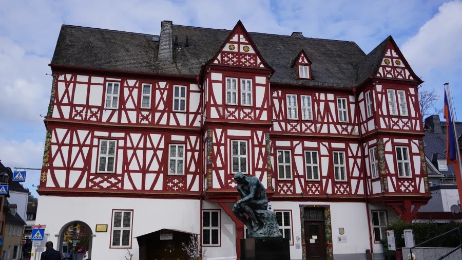 Historisches Fachwerkhaus in Nassau mit roter und weißer Fassade und einer Statue im Vordergrund.