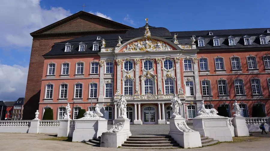 Fassade des kurfürstlichen Palais in Trier mit barocker Architektur und Skulpturen im Vordergrund.