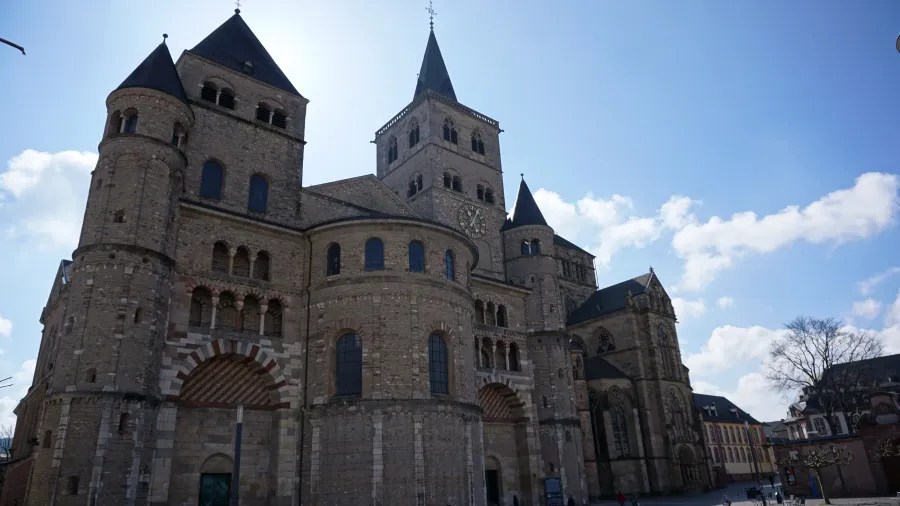 Der Trierer Dom, eine monumentale romanische Kirche, steht majestätisch unter einem klaren, blauen Himmel.