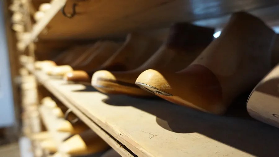 Holzschuhleisten auf einem Regal in einem Museum, das die Geschichte der Schuhproduktion zeigt.