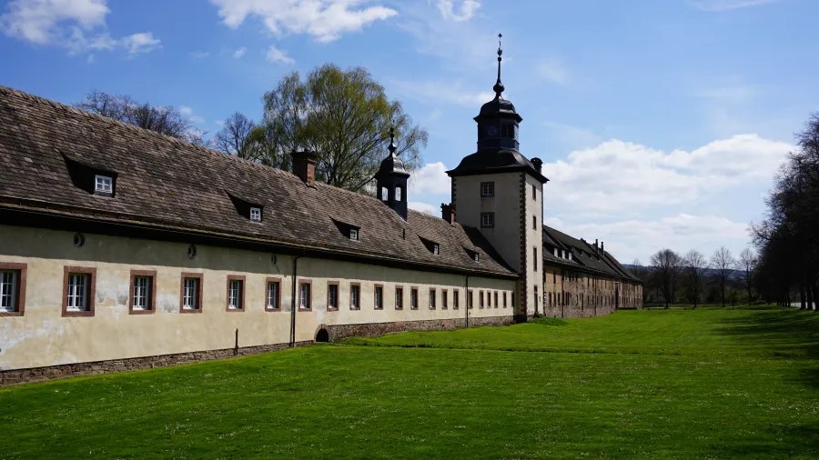 Historic building with a tower and grassy area under a blue sky