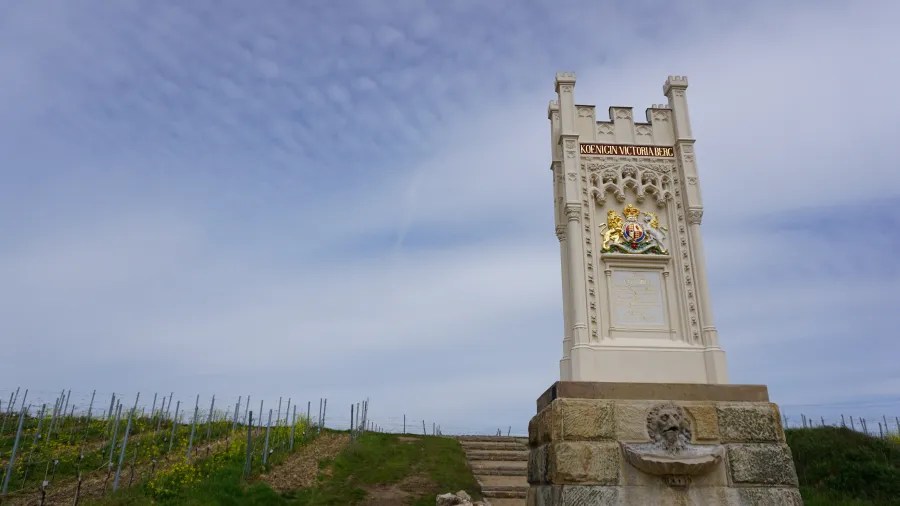 Ein historisches Denkmal steht in einem Weinberg unter einem bewölkten Himmel.