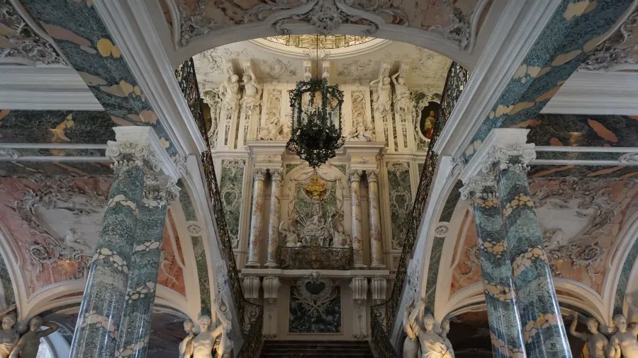 Der beeindruckende Innenraum des Schlosses Augustusburg mit opulenten Säulen und kunstvoller Deckenmalerei im Rokokostil.