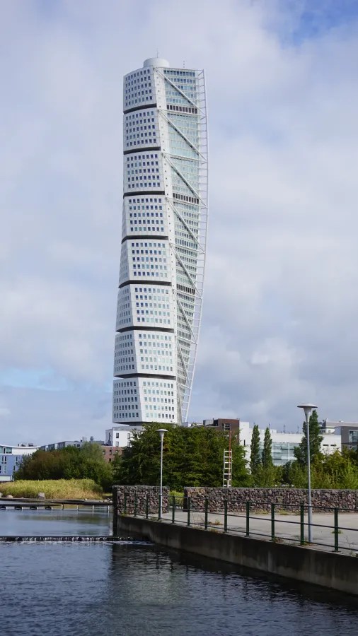 Der Turning Torso in Malmö, ein markanter und drehender Wolkenkratzer, umgeben von einer ruhigen Wasserfläche und moderner Architektur.