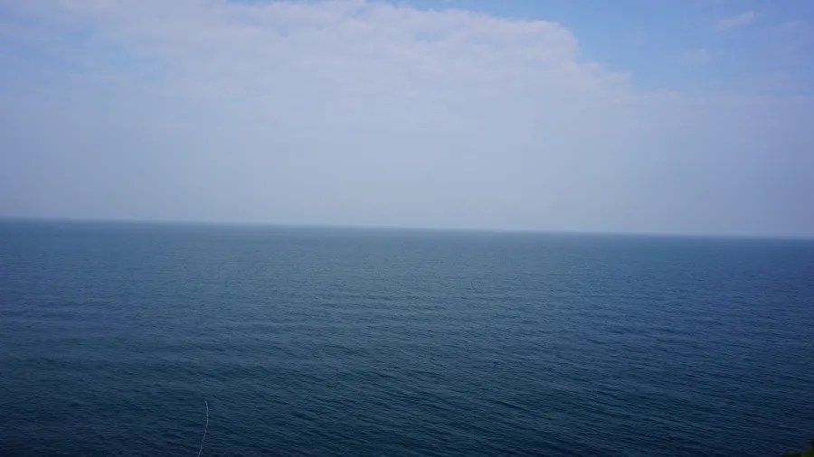 Blick auf das ruhige, blaue Wasser des Atlantischen Ozeans unter einem leicht bewölkten Himmel.