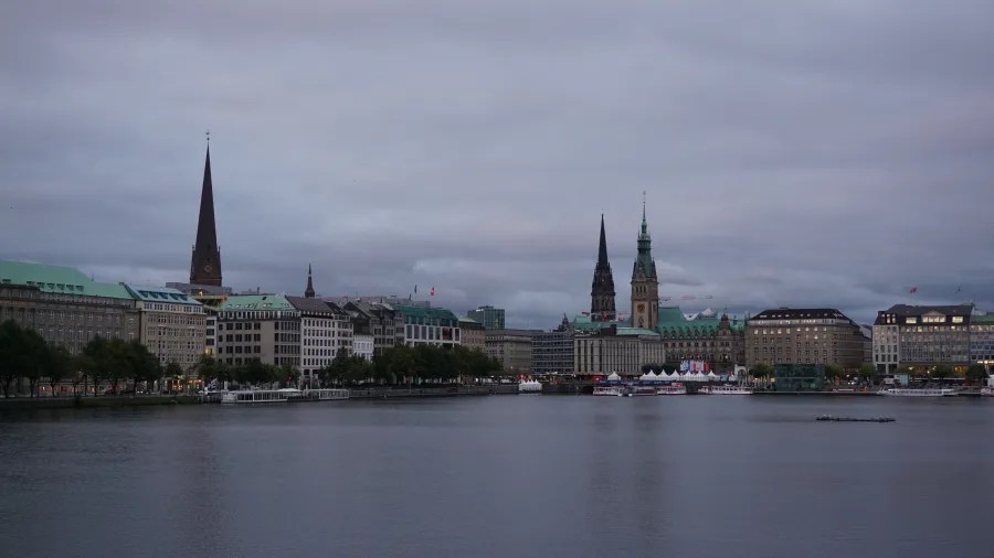 Blick auf die Hamburger Binnenalster mit markanten Gebäuden und Kirchtürmen im Hintergrund während eines bewölkten Morgens.