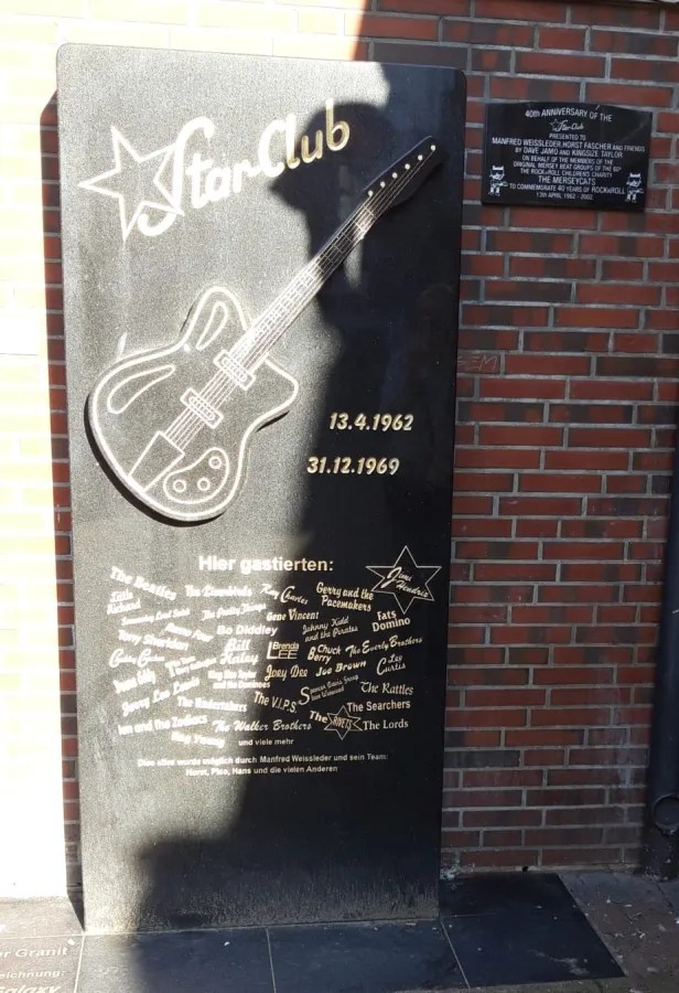 Gedenktafel des Star Clubs in Hamburg mit einem Gitarrenmotiv und den Namen bekannter Künstler, die dort auftraten.