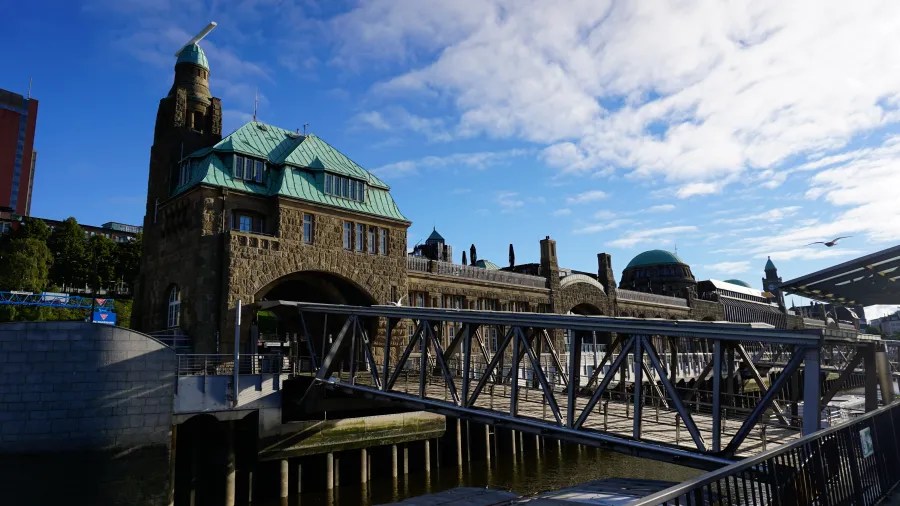 Blick auf ein historisches Gebäude mit grünem Dach in Hamburg, Deutschland, umgeben von Wasser und einem blauen Himmel.