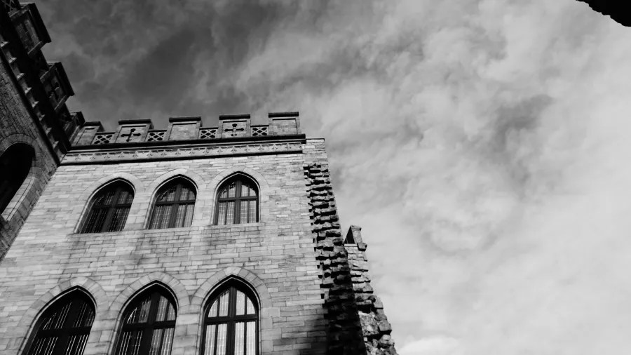 Blick auf das Hambacher Schloss mit gotischen Fenstern und Wolken im Hintergrund, in Schwarz-Weiß.