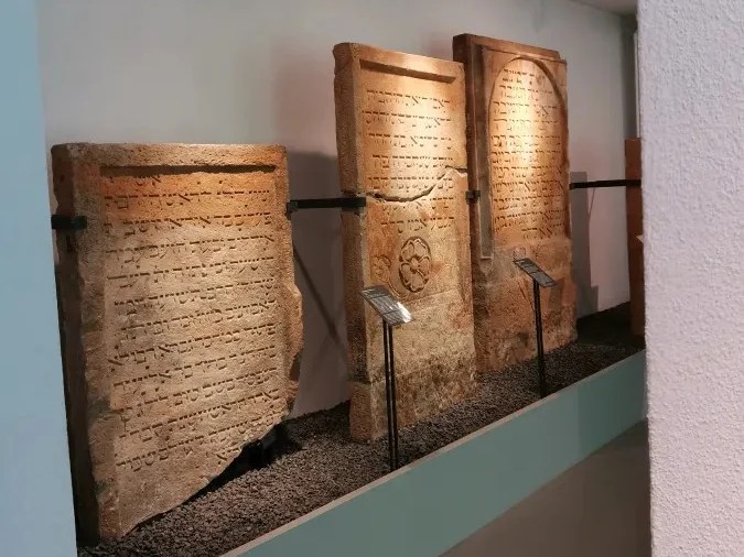 Drei antike Steintafeln mit Inschriften, ausgestellt in einem Museum.