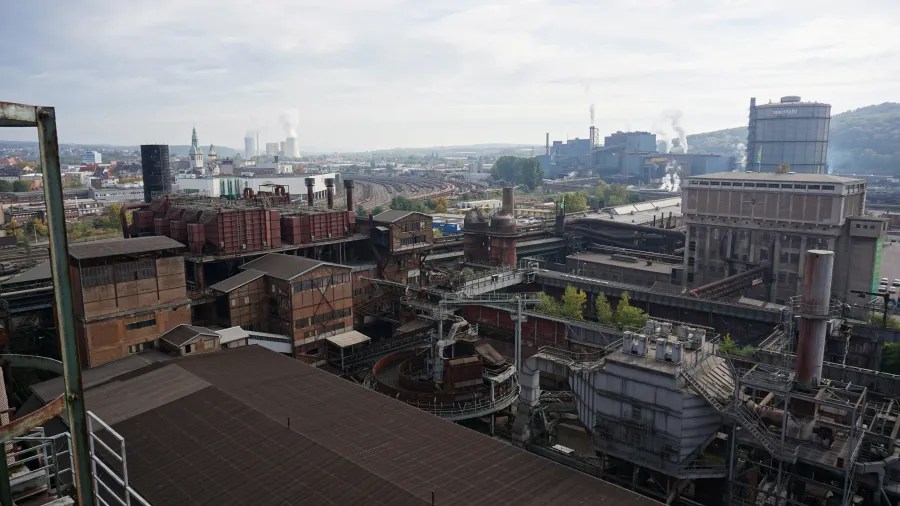 Blick auf die Völklinger Hütte mit Industrieanlagen und rauchenden Schornsteinen im Hintergrund.