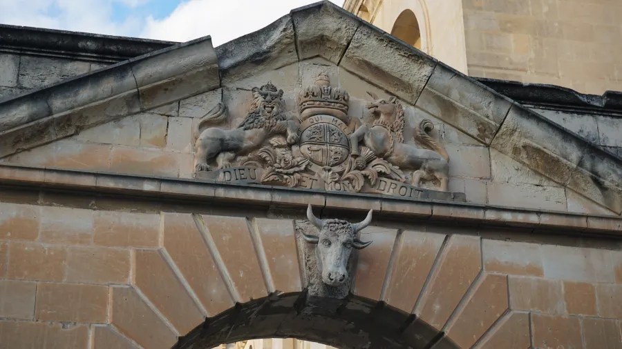 Ein historisches Wappen mit Löwen und einem Kopf eines Tieres über einem Torbogen.