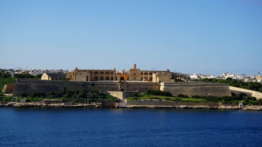 Blick auf Fort Manoel in Valletta, Malta, umgeben von blauem Wasser und sommerlichem Himmel.