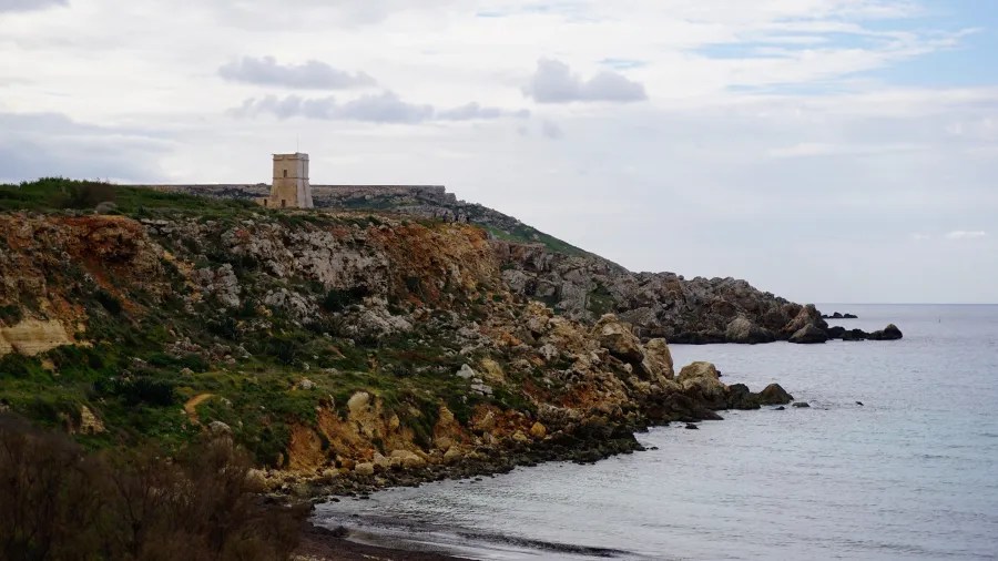 Ein historischer Aussichtsturm auf einer Klippe mit einem malerischen Meer im Vordergrund und einem bewölkten Himmel im Hintergrund.