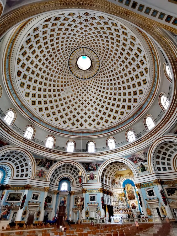 Blick auf die kunstvoll gestaltete Kuppel einer Kirche mit geometrischen Mustern und goldenen Verzierungen im Innenraum.