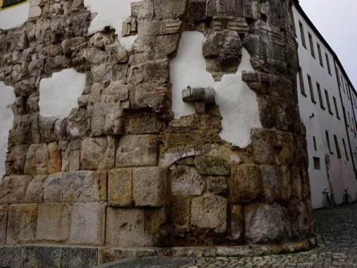 Ein historisches Mauerwerk mit sichtbar abblätterndem Putz und unverputzten Steinflächen, das an einer Ecke eines Gebäudes zu sehen ist.
