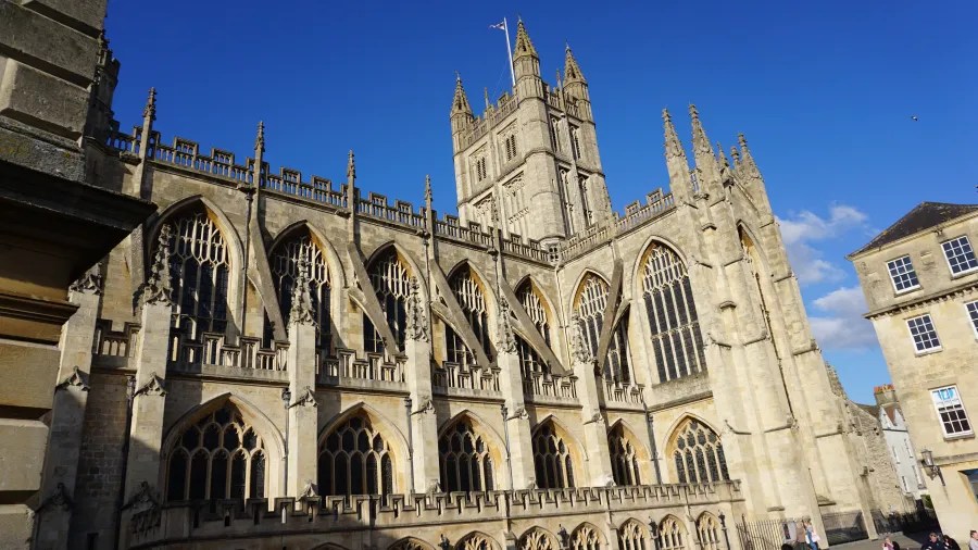 Ansicht der Fassade einer alten Kathedrale mit gotischer Architektur und hohen Türmen vor einem blauen Himmel.