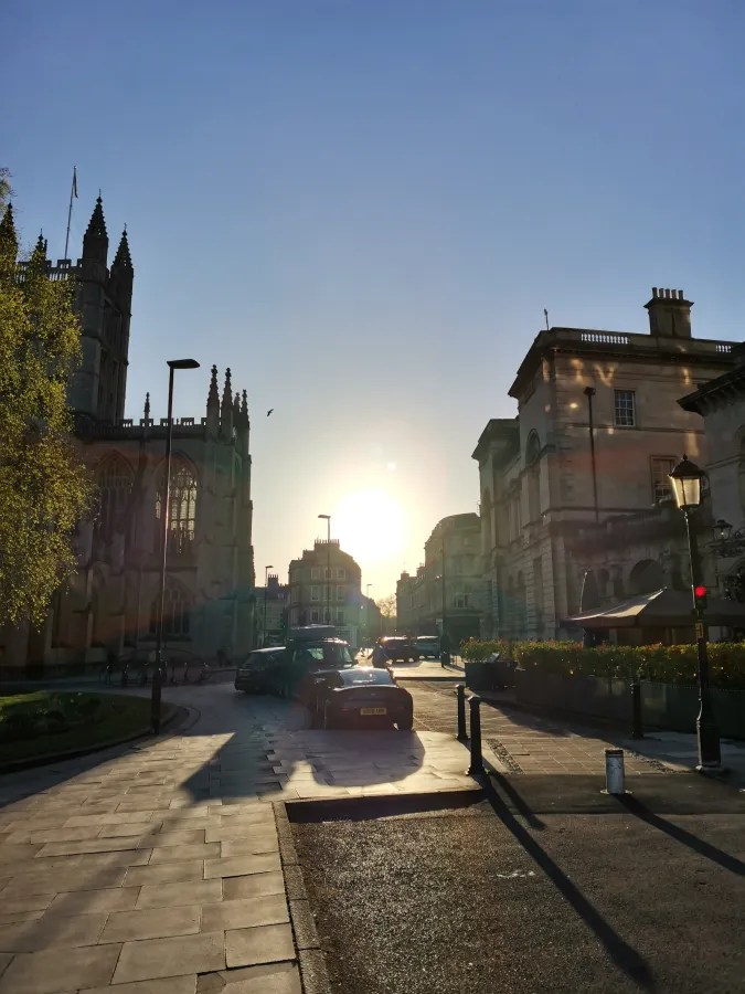 Sonnenuntergang über einer städtischen Straße, flankiert von historischen Gebäuden.