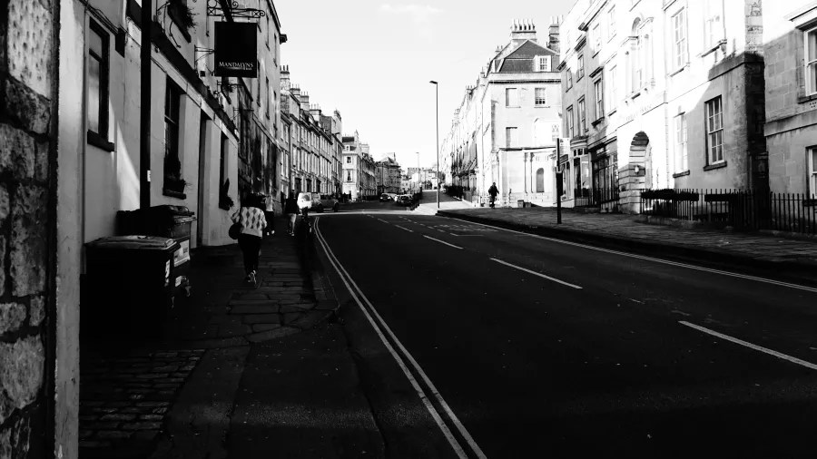 Eine Straßenansicht mit historischen Gebäuden, einer leeren Straße und einem joggenden Passanten, aufgenommen in Schwarz-Weiß.