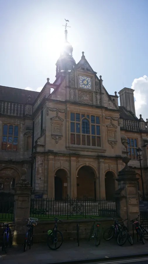 Historisches Gebäude mit Uhr und Sonnenschein im Hintergrund, Fahrräder im Vordergrund.