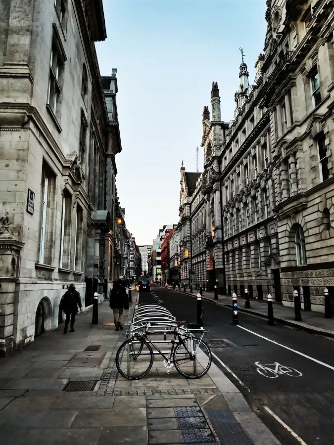Eine ruhige Stadtstraße mit historischen Gebäuden und einer Fahrradabstellanlage im Vordergrund.
