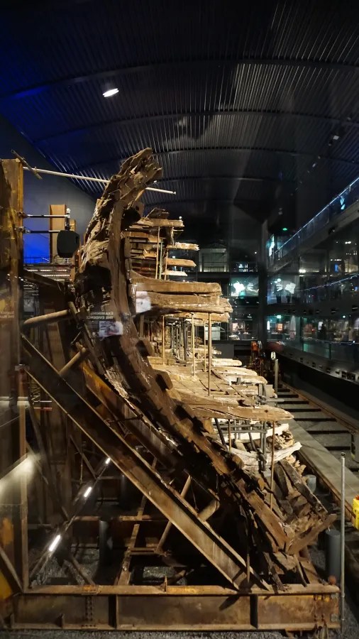 Ein historisches Schiffswrack, das in einem Museum ausgestellt ist, mit gut erhaltenen Holzstrukturen und einem modernen Ausstellungsdesign im Hintergrund.