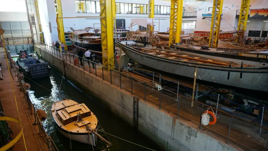 Blick auf ein Schiffsdock mit mehreren Booten und Yachten, einige stehen auf Werkbänken, andere im Wasser.