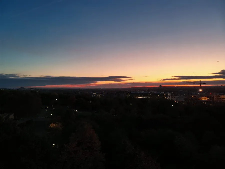 Sonnenuntergang über einer Stadtlandschaft mit einem klaren Himmel und farbigen Wolken.
