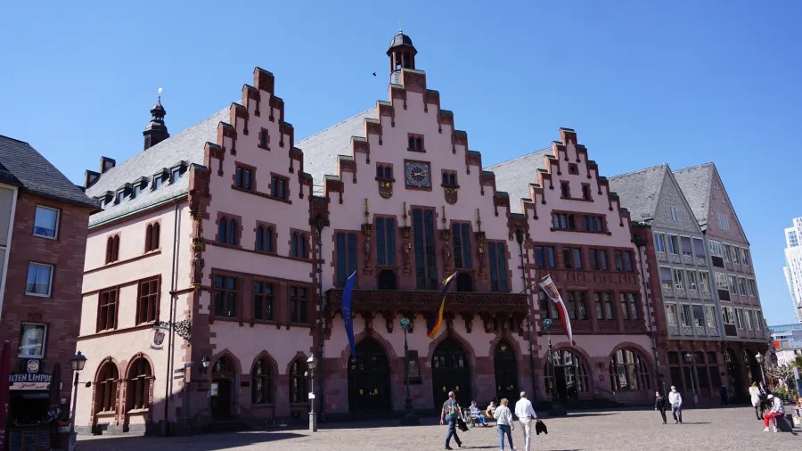 Das Bild zeigt das historische Römerhaus in Frankfurt am Main, ein Wahrzeichen der Stadt mit gotischer Architektur und dekorativen Elementen. Der klare blaue Himmel ergänzt die Szenerie.