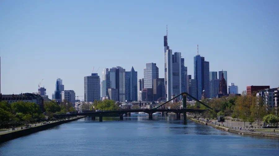 Blick auf die Skyline von Frankfurt am Main mit modernen Wolkenkratzern und dem Fluss Main im Vordergrund.