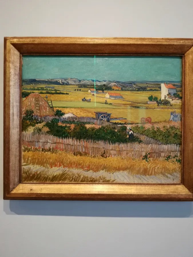 Gemälde einer ländlichen Landschaft mit Feldern, einem Heuhaufen und einem Bauern, der arbeitet, umgeben von Zäunen und Gebäuden unter einem klaren Himmel.