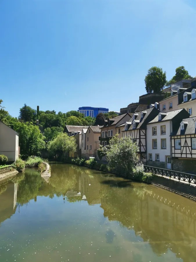 Ein ruhiger Fluss fließt durch eine malerische Stadt mit traditionellen Häusern und einer klaren blauen Himmel im Hintergrund.