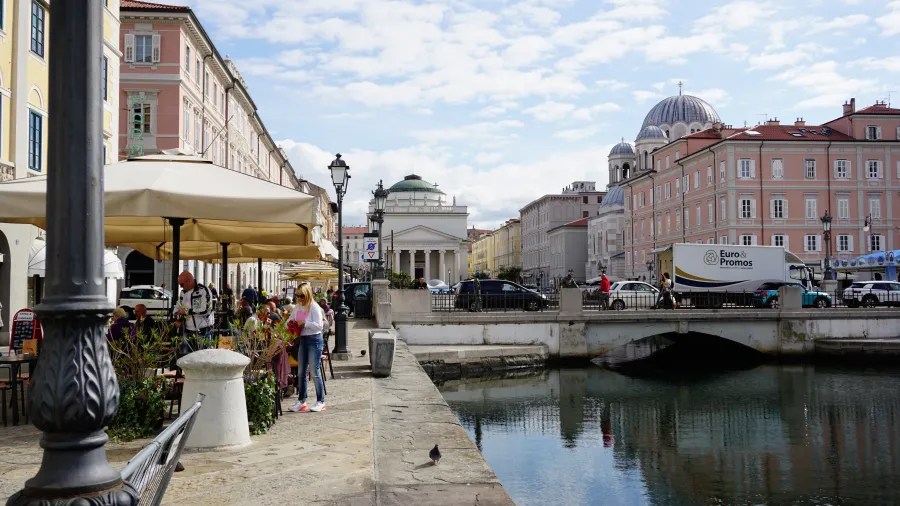 Ein malerischer Kanal mit Restaurants und Cafés, umgeben von historischen Gebäuden und einem auffälligen Dom im Hintergrund.