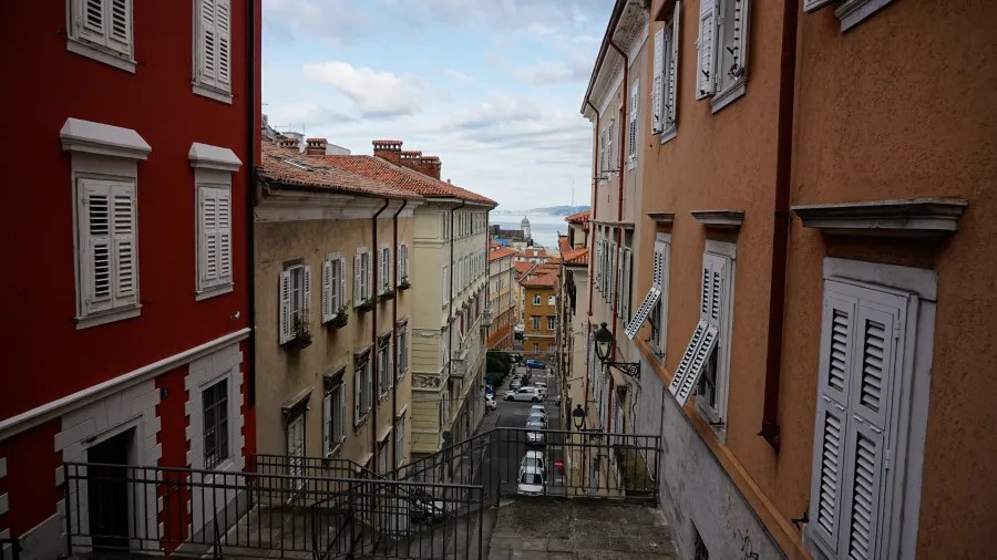 Blick auf eine schmale Straße mit farbigen Gebäuden in einer Küstenstadt.