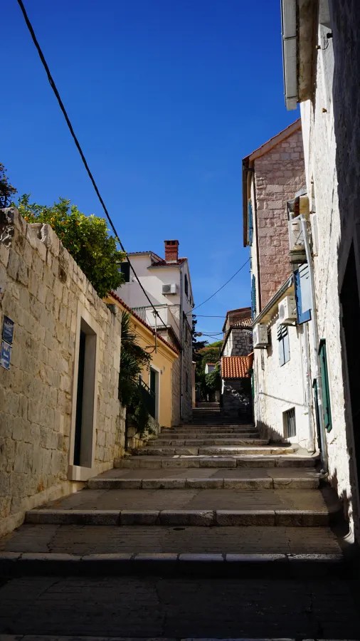 Narrow stone steps leading up between old buildings under a clear blue sky.