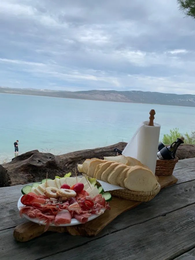 Appetizer platter and sliced bread on a wooden table overlooking a scenic lake