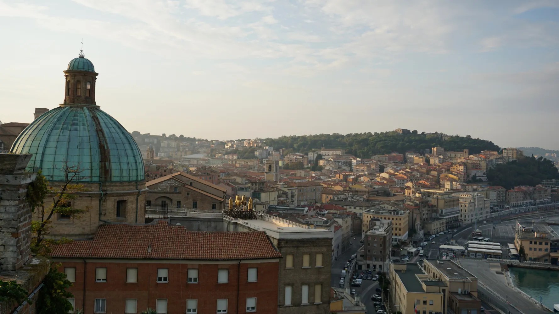 Cityscape of Ancona, Italy, featuring a prominent green dome and the harbor.