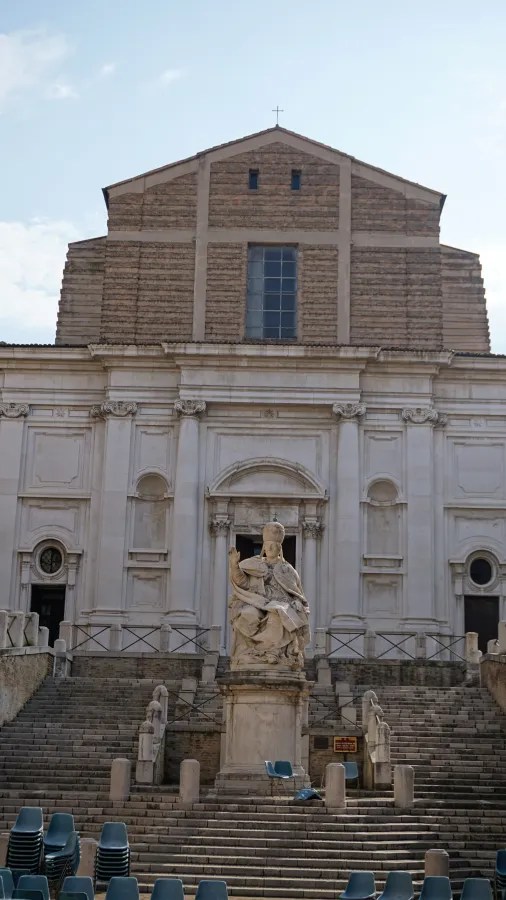 Historic stone cathedral facade with a central statue atop wide outdoor steps