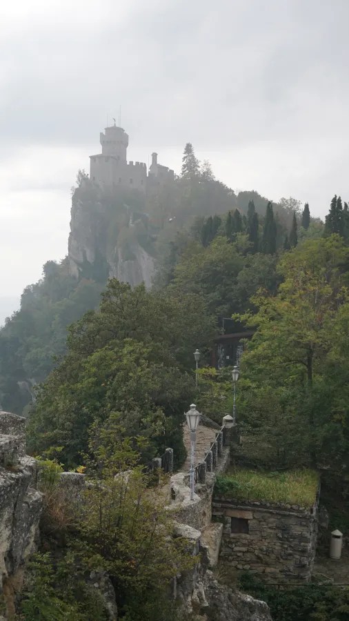 Stone fortress perched on a rocky cliff surrounded by misty forests