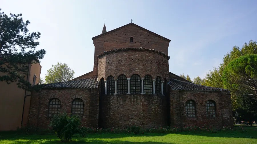 The rear exterior of a historic brick church with a rounded apse and arched windows