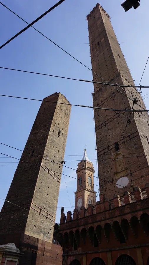 Low-angle view of the two medieval towers of Bologna, one leaning, against a clear sky