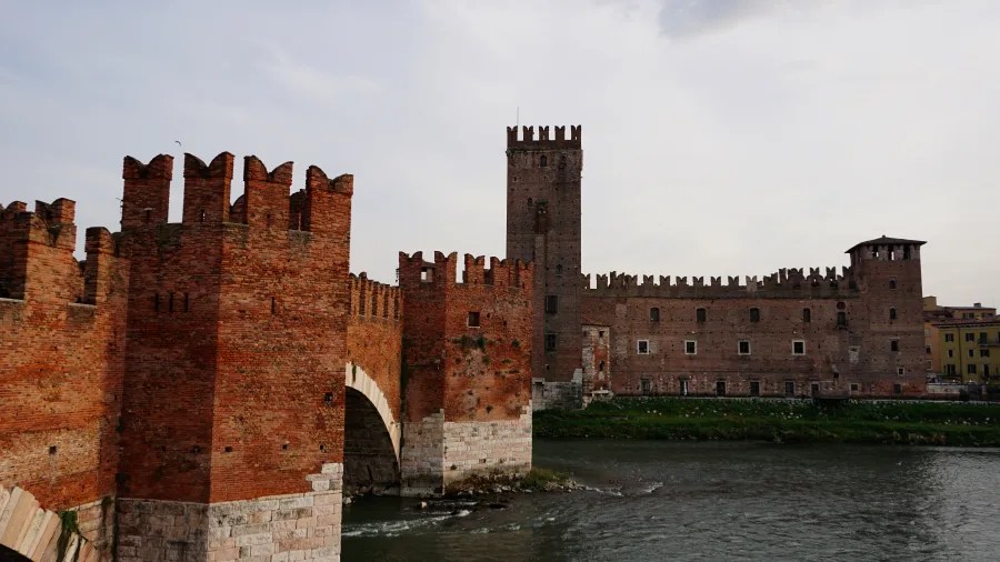 Red brick medieval fortress and fortified bridge with battlements over a river
