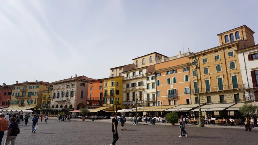 Colorful historic buildings and outdoor cafes lining a wide, paved public square