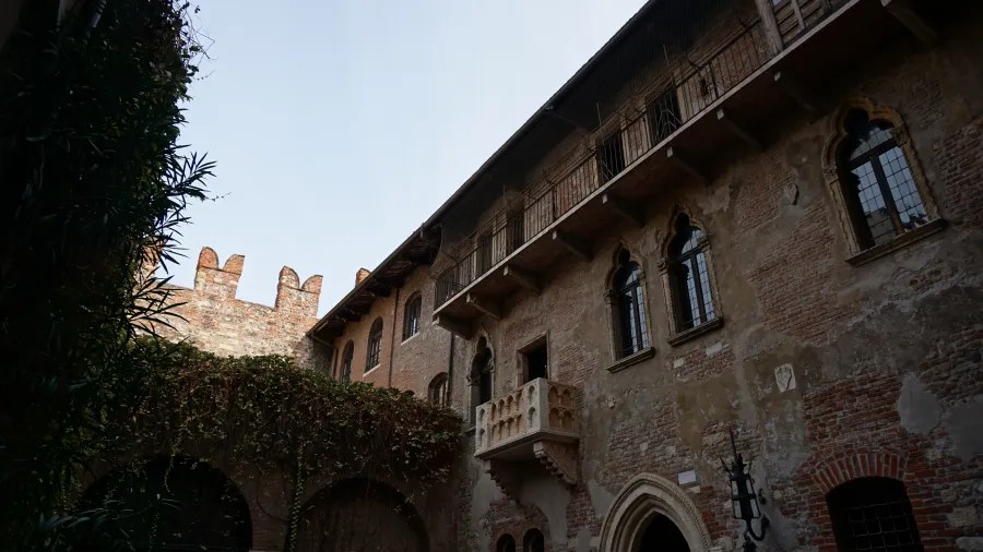 The iconic stone balcony and historic brick facade of Juliet's House in Verona, Italy.