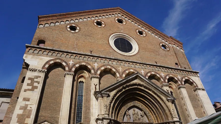 Facade of a historic brick church featuring circular windows and an ornate arched entryway.
