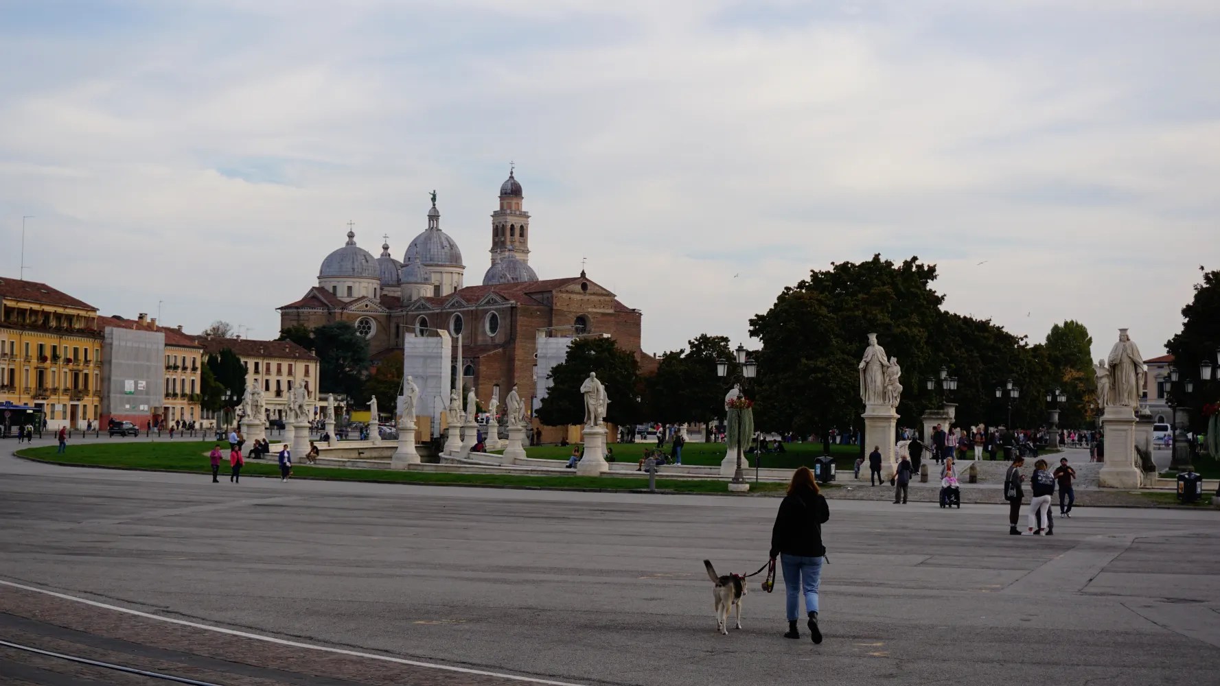 People walking in Prato della Valle square with the Abbey of Santa Giustina in the background.