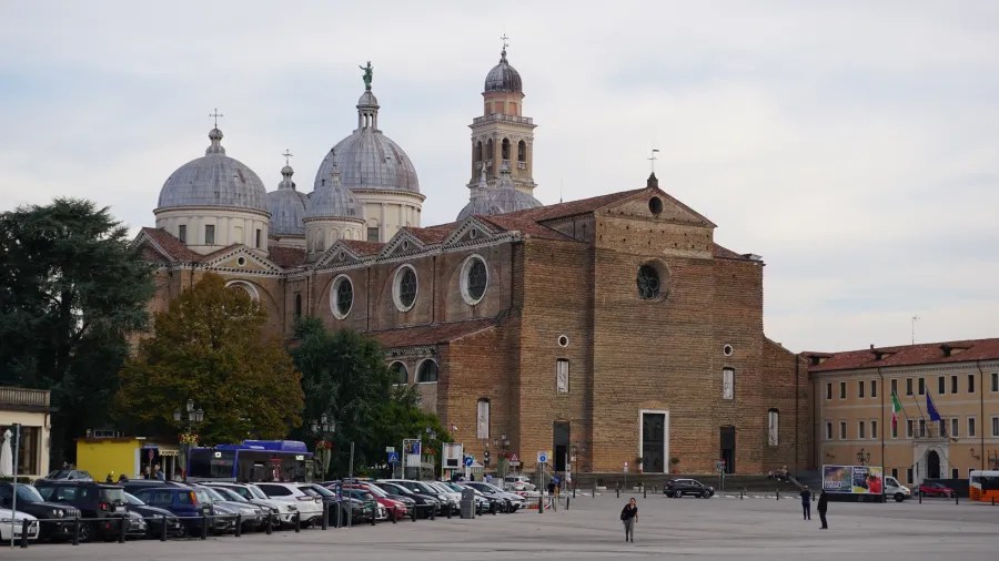 Brick Abbey of Santa Giustina with multiple white domes and a bell tower in Padua.