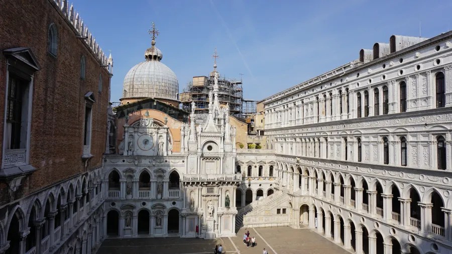 Ornate courtyard of the Doge's Palace in Venice with views of St. Mark's Basilica dome.