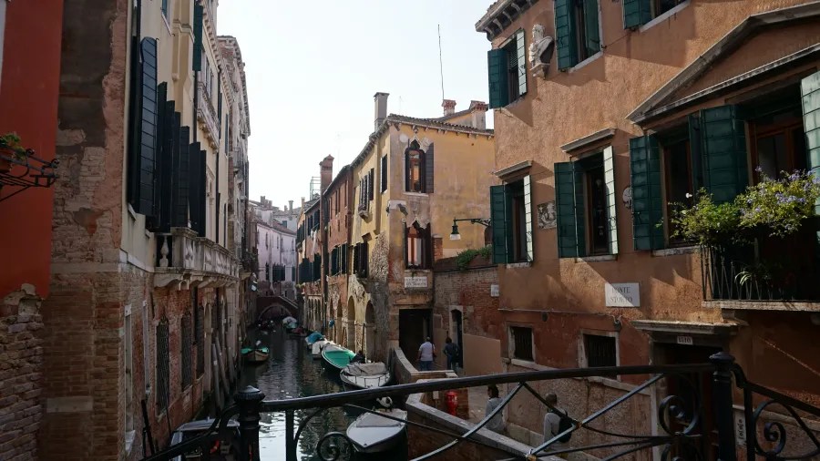 Boats moored along a narrow canal between historic buildings in Venice, Italy