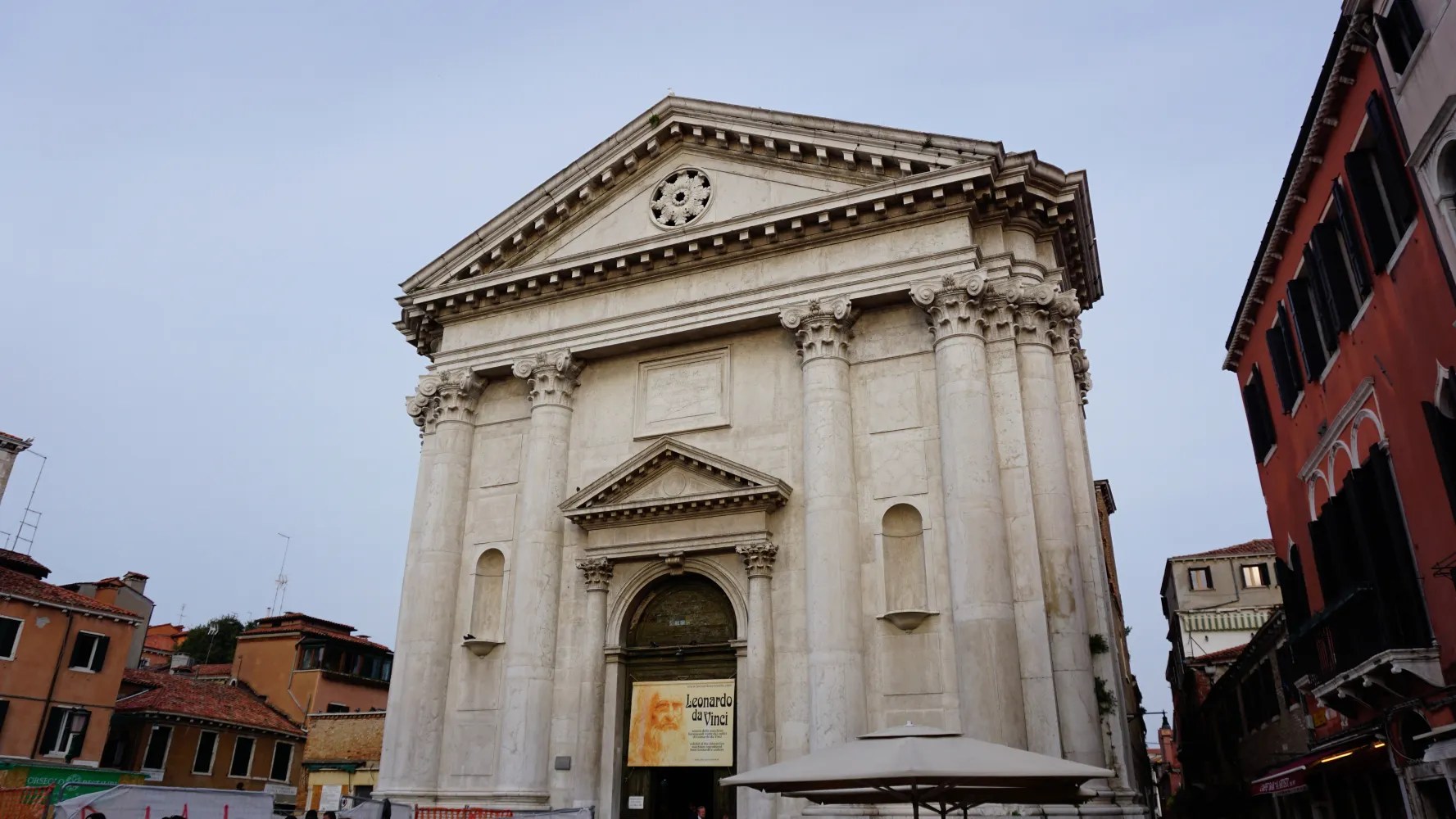 White classical stone building with columns and a banner advertising a Leonardo da Vinci exhibition